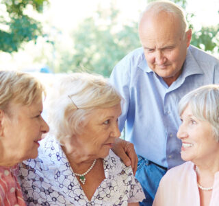 Long-awaited gathering of best friends Senior friends having tea party in lovely summer cafe and sharing latest news with each other; two women putting arms on each others shoulders